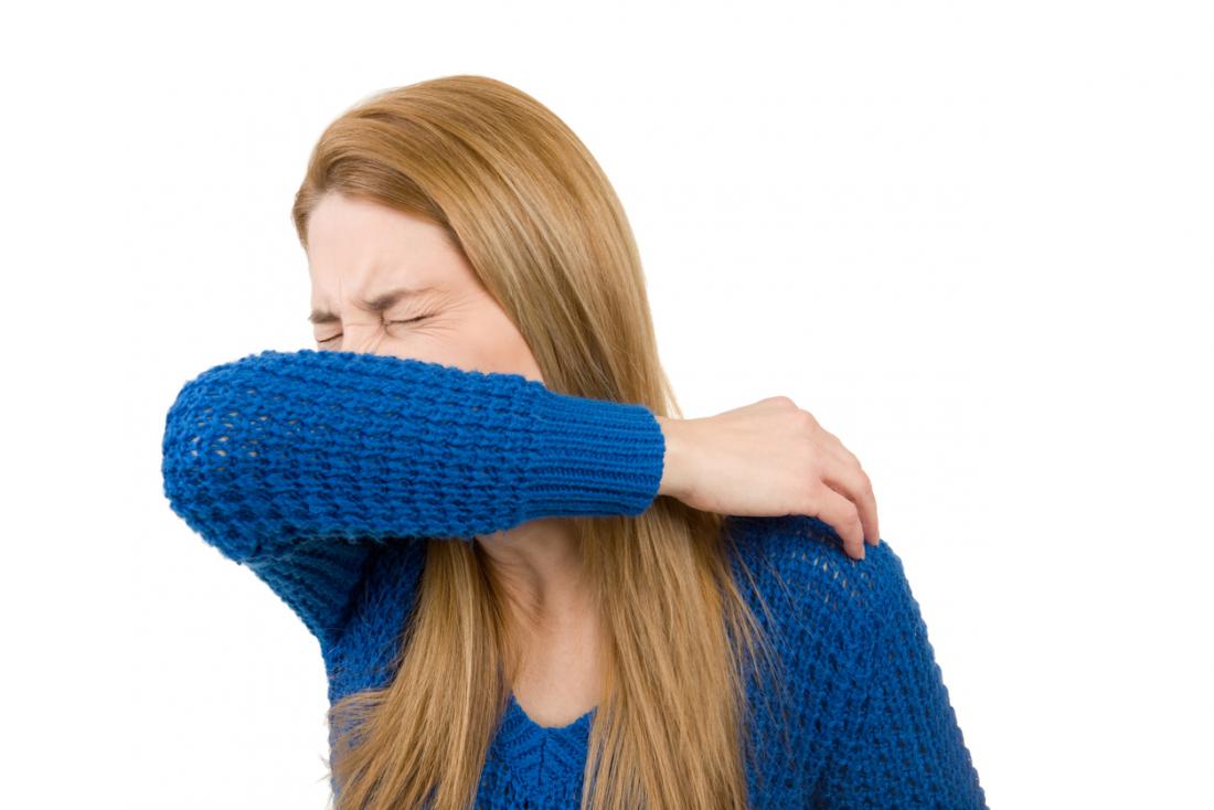 woman sneezing into her elbow