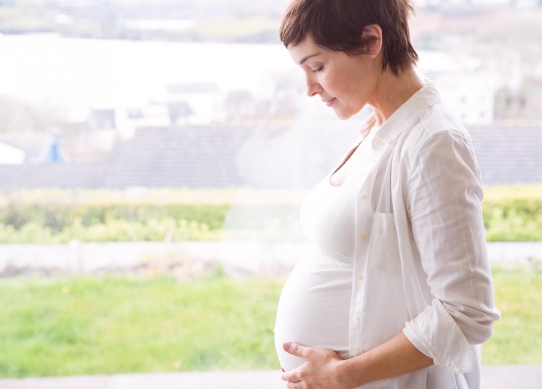pregnant woman standing by window