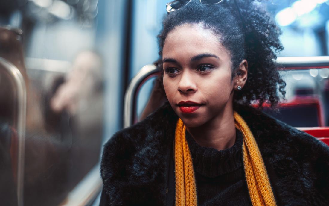 a woman with depression looking out the window on a bus. 