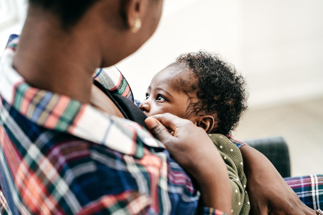 a woman in a colourful top breastfeeding her baby. 