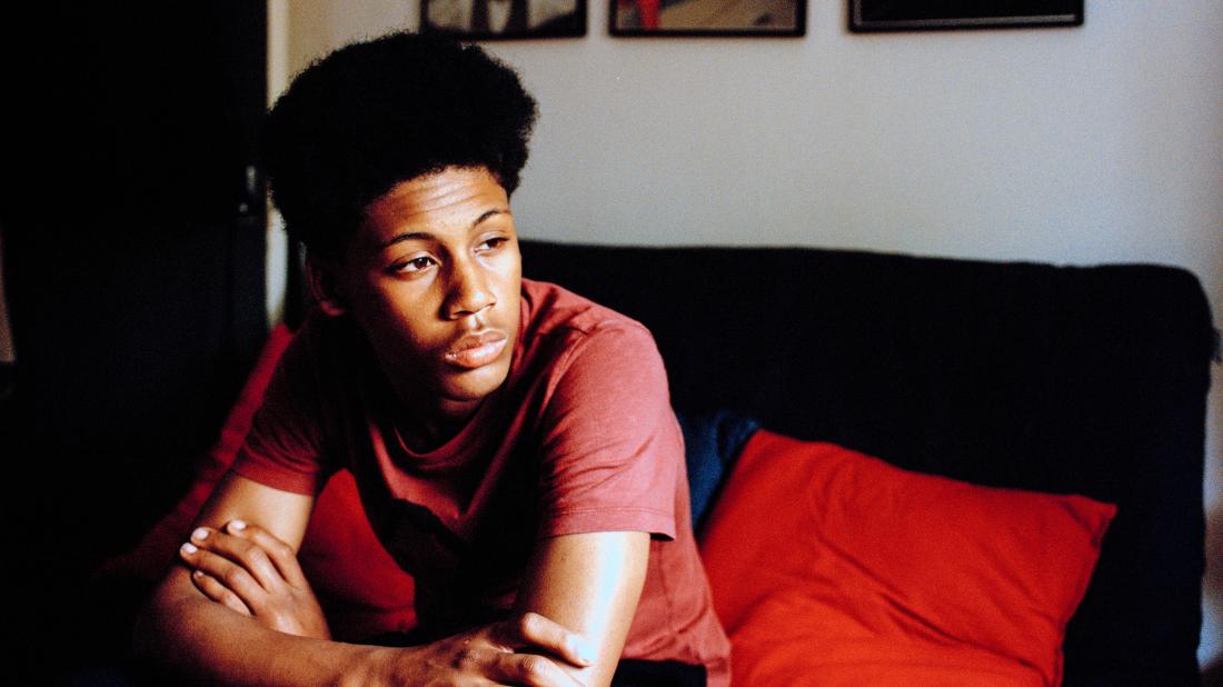 a teenage boy looking pensive as he thinks about the symptoms of gonorrhea