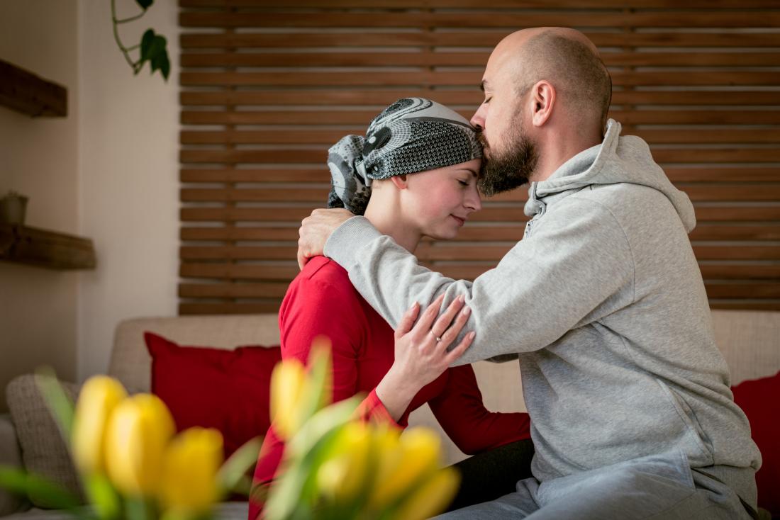 man kisses female cancer survivor on head