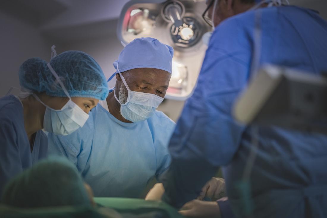 surgeons performing operation in masks and gowns