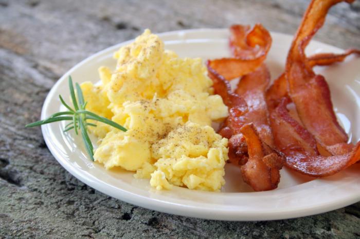Scrambled eggs and bacon on plate.