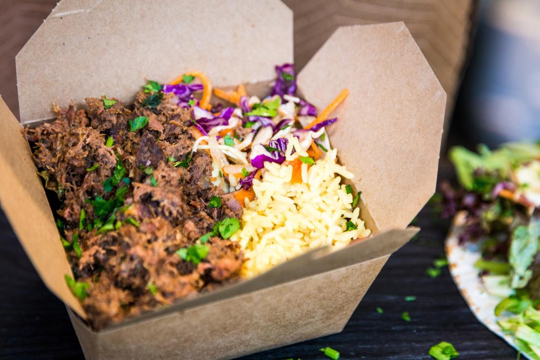 Pulled pork, rice and salad in takeaway box.