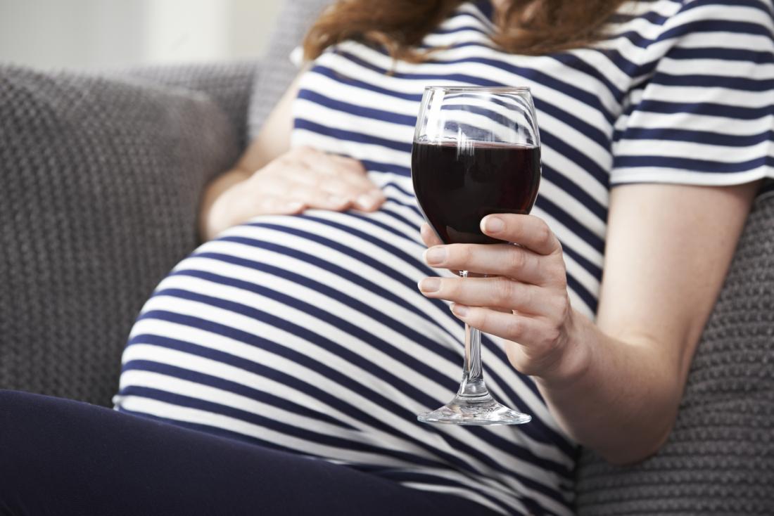 Pregnant woman holding a glass of wine.