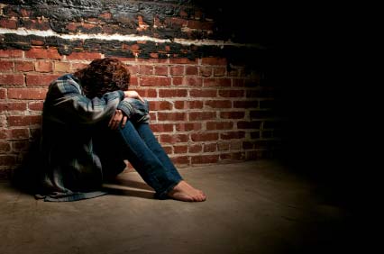 Depressed girl sitting by wall