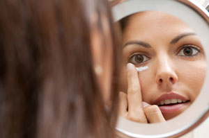 Young woman applying moisturizer