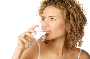 A lady drinks a glass of water