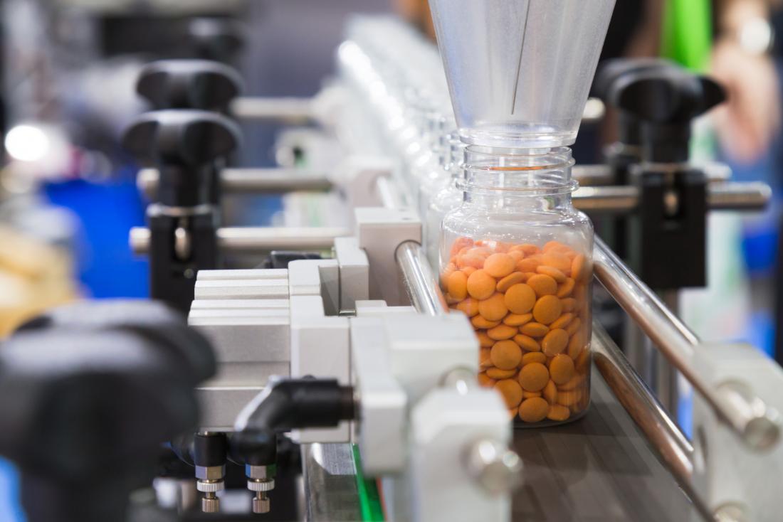 Bottles of medication pills or pharmaceutical drugs being made in factory production line.