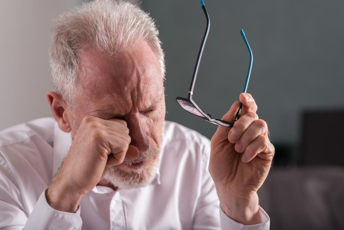 man rubbing eyes