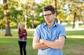 Photo of man standing with arms crossed, woman behind