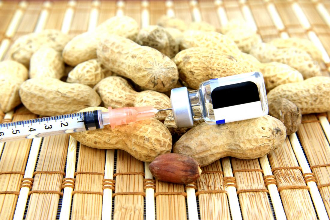 Peanut allergy represented by pile of peanuts with syringe needle for immunotherapy.