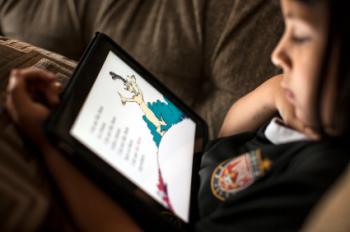 girl reading from an ipad in bed