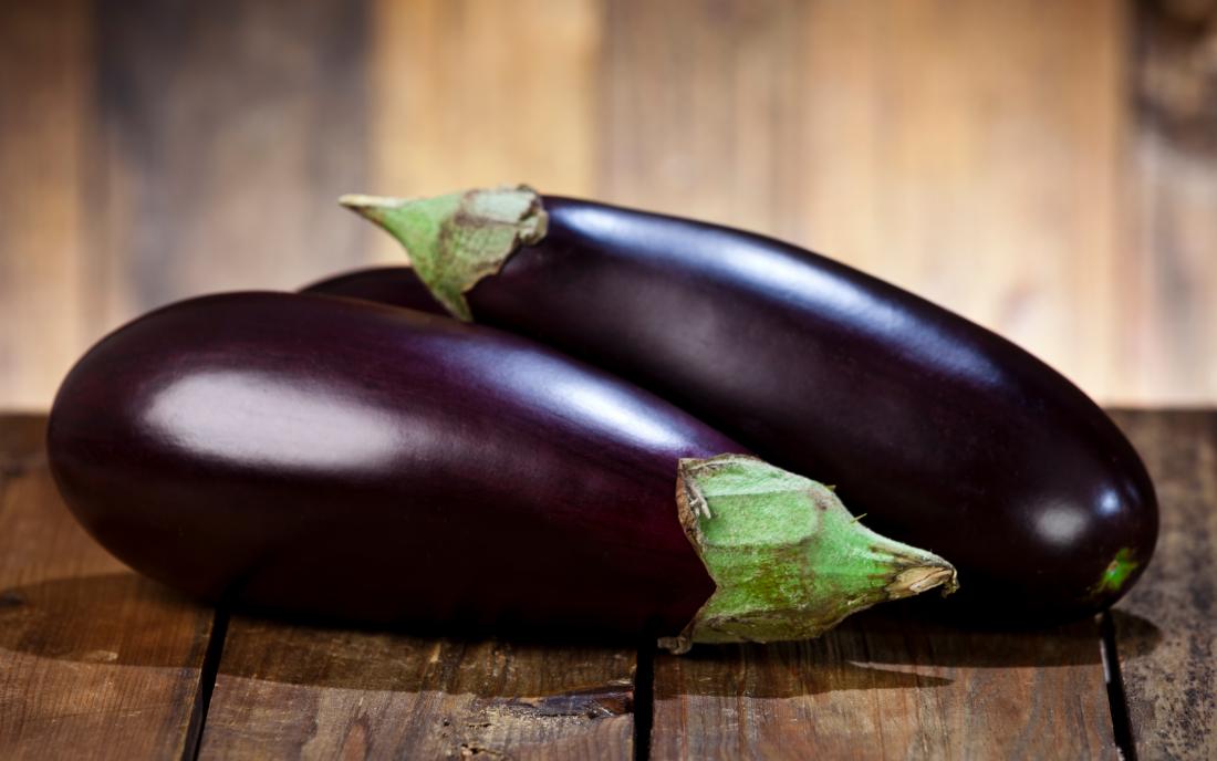 two eggplants on a wooden table. 