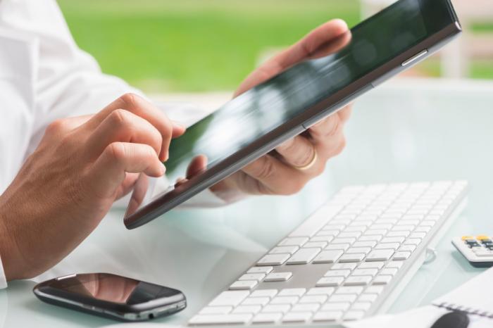 man using a cellphone tablet and computer
