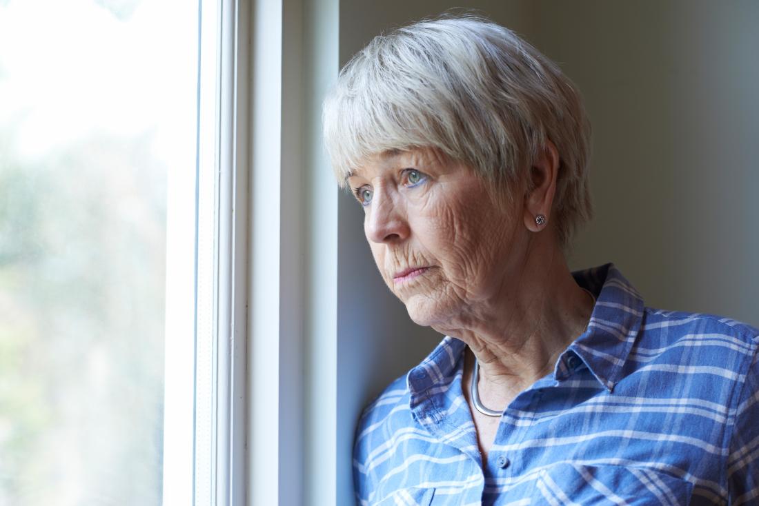 Depressed senior older woman looking out of window