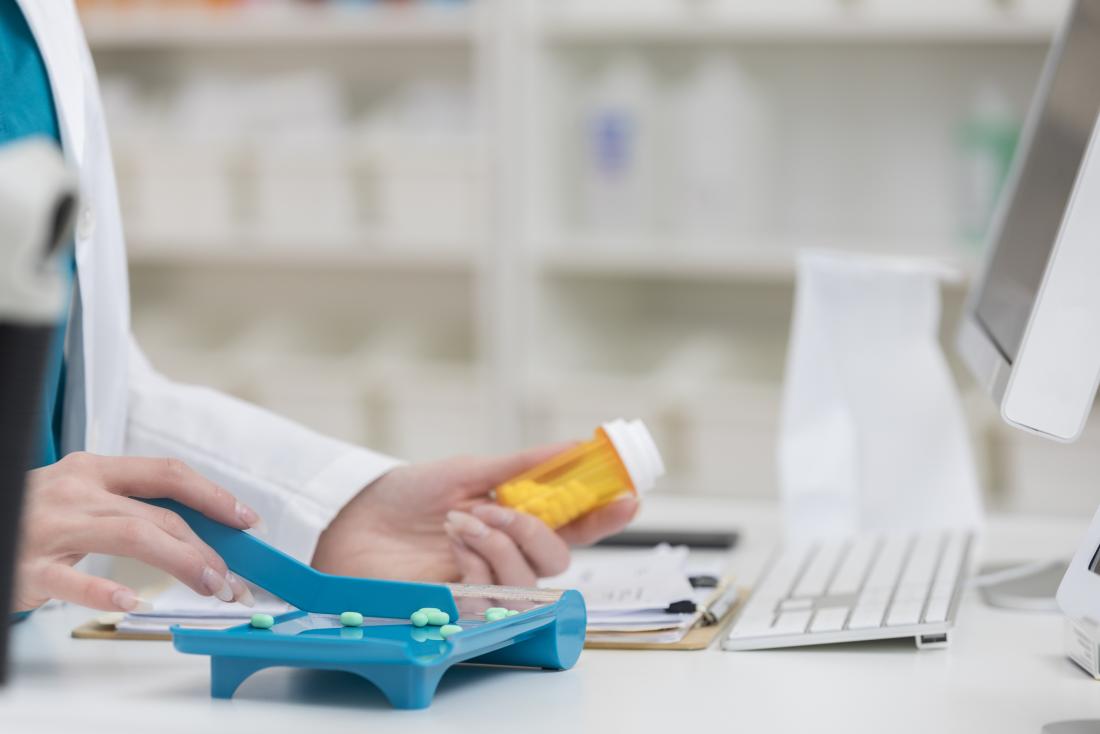 Pharmacist with pills measuring out medication prescription