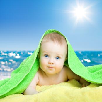 A child on the beach covered by a towel