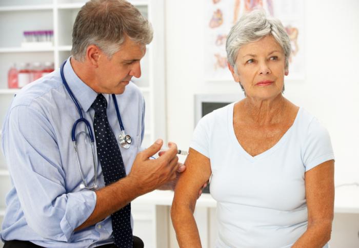 Male physician vaccinating an older lady.