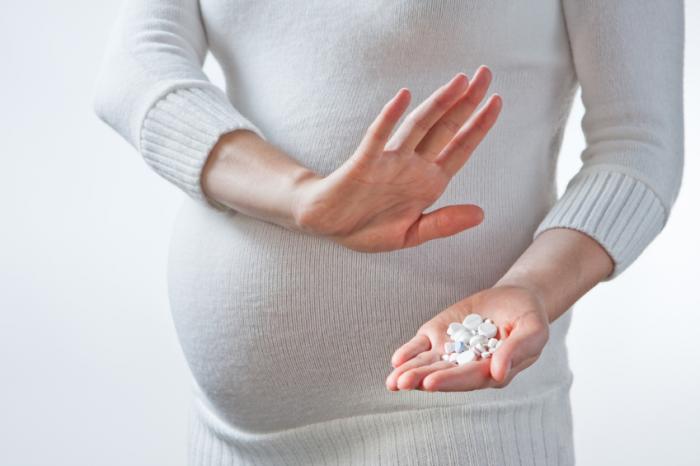 A pregnant woman holding pills