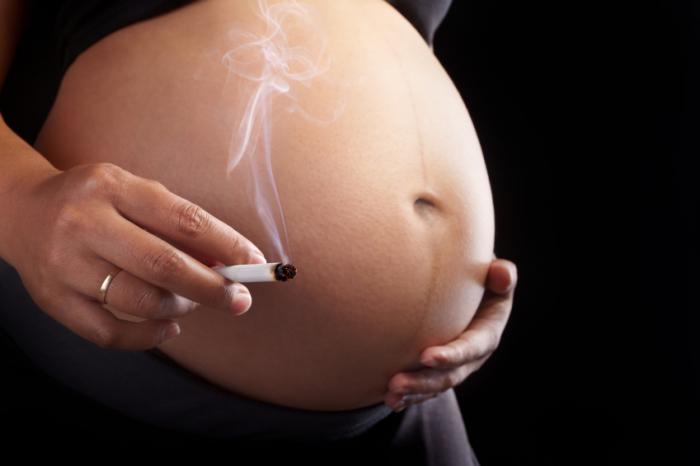 A pregnant woman is smoking a cigarette.