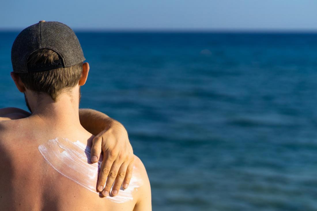 Man rubbing sunscreen into his back