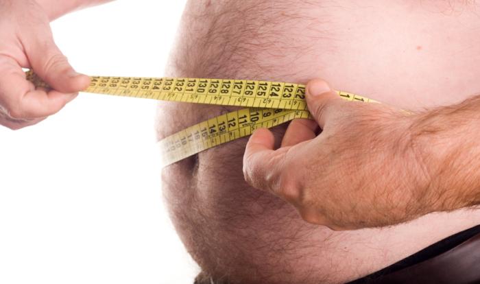 An obese man measuring his waist