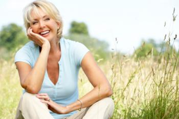 A mature woman sitting down outside.