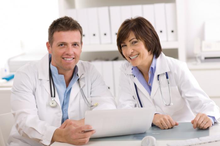 A male and a female doctor sit together.