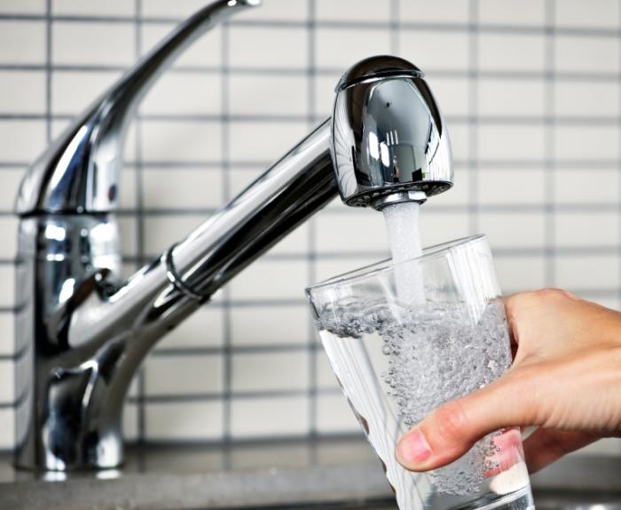 Filling glass with water from a tap.