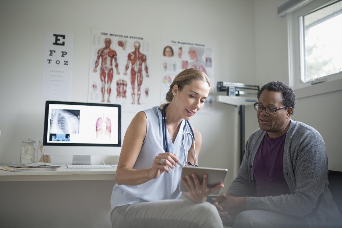doctor showing patient the appearance of herpes with pictures on tablet device