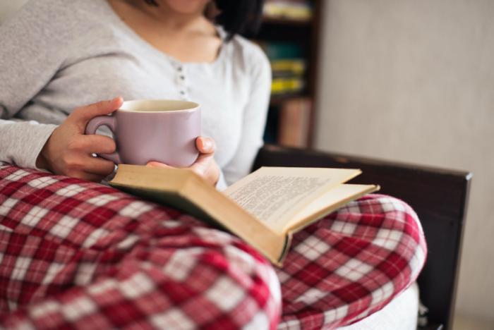 Woman with mug reading in pyjamas.