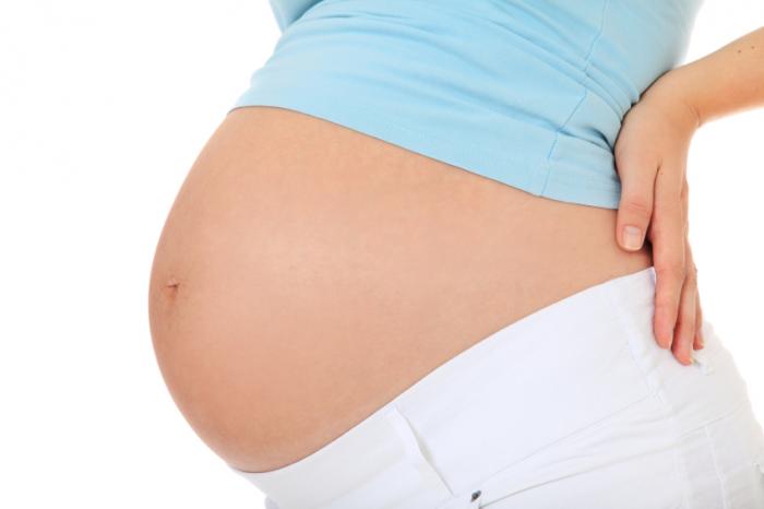 A pregnant woman holding her back.