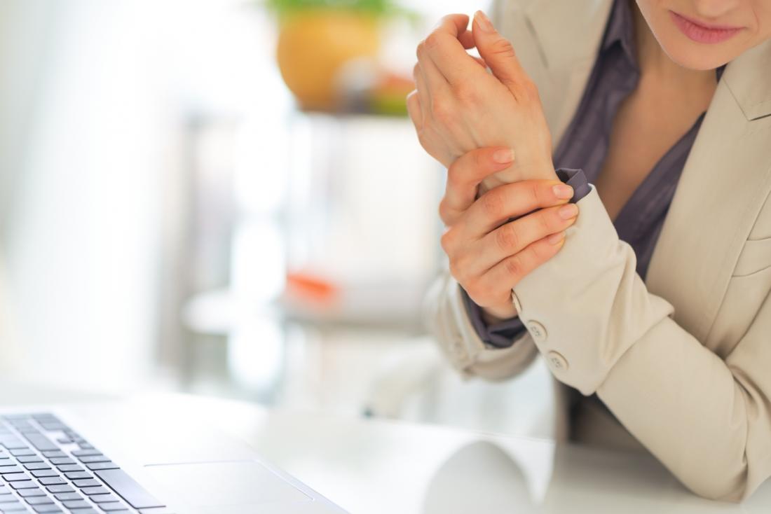 Woman holding her wrist after experiencing pain while typing.