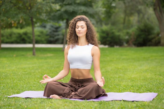 A woman is meditating in a park.