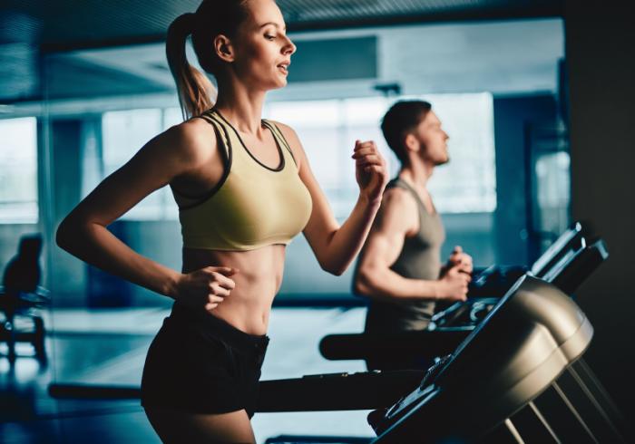 Two people are running in a gym.