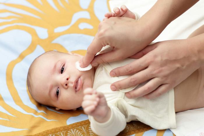 A baby is having its face cleaned.