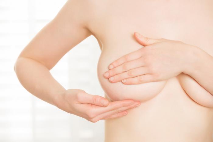 woman checks breast for any signs of breast cancer