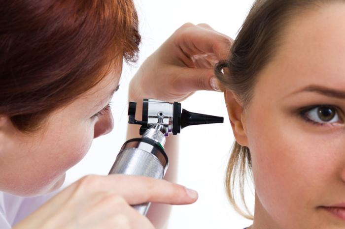 A doctor examines a ladies right ear with an otoscope
