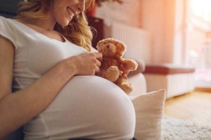 A pregnant mother holds a teddy bear