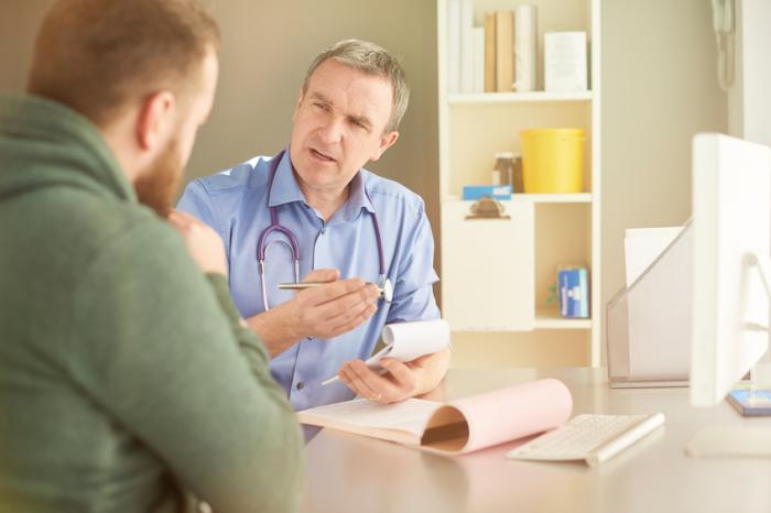 A doctor speaks with a patient in his office