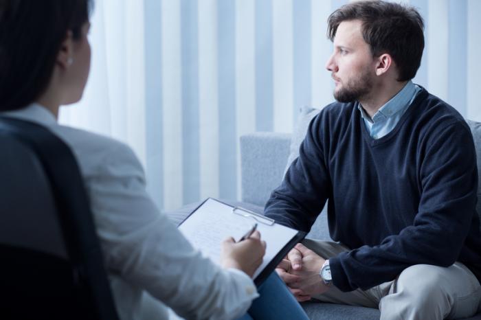A man sits opposite a counsellor looking away