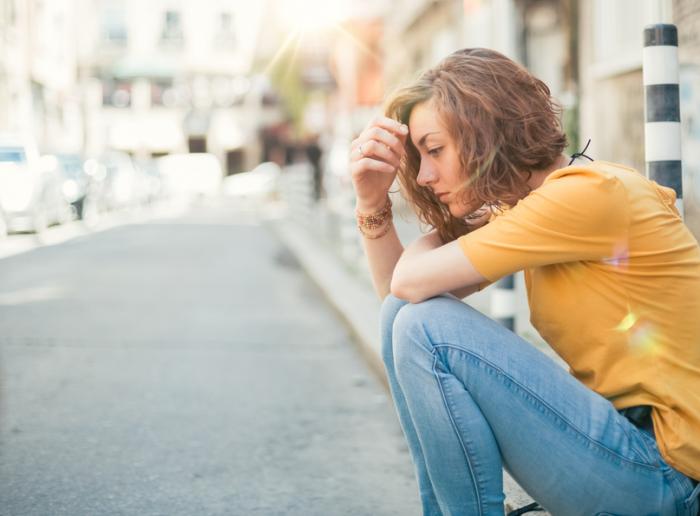 A lady sits down looking despondent