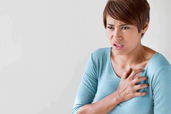 A woman clutching her heart with chest pain