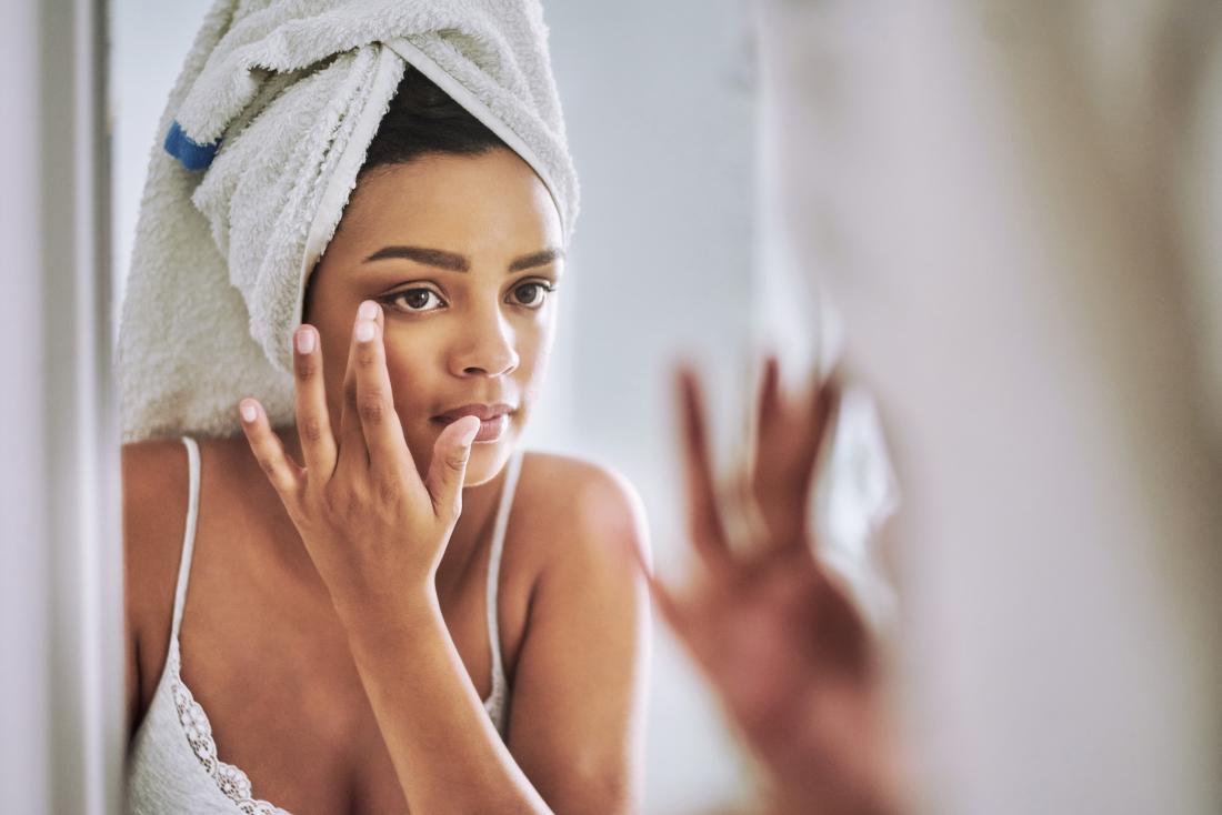 young woman looking at eyelid in the mirror