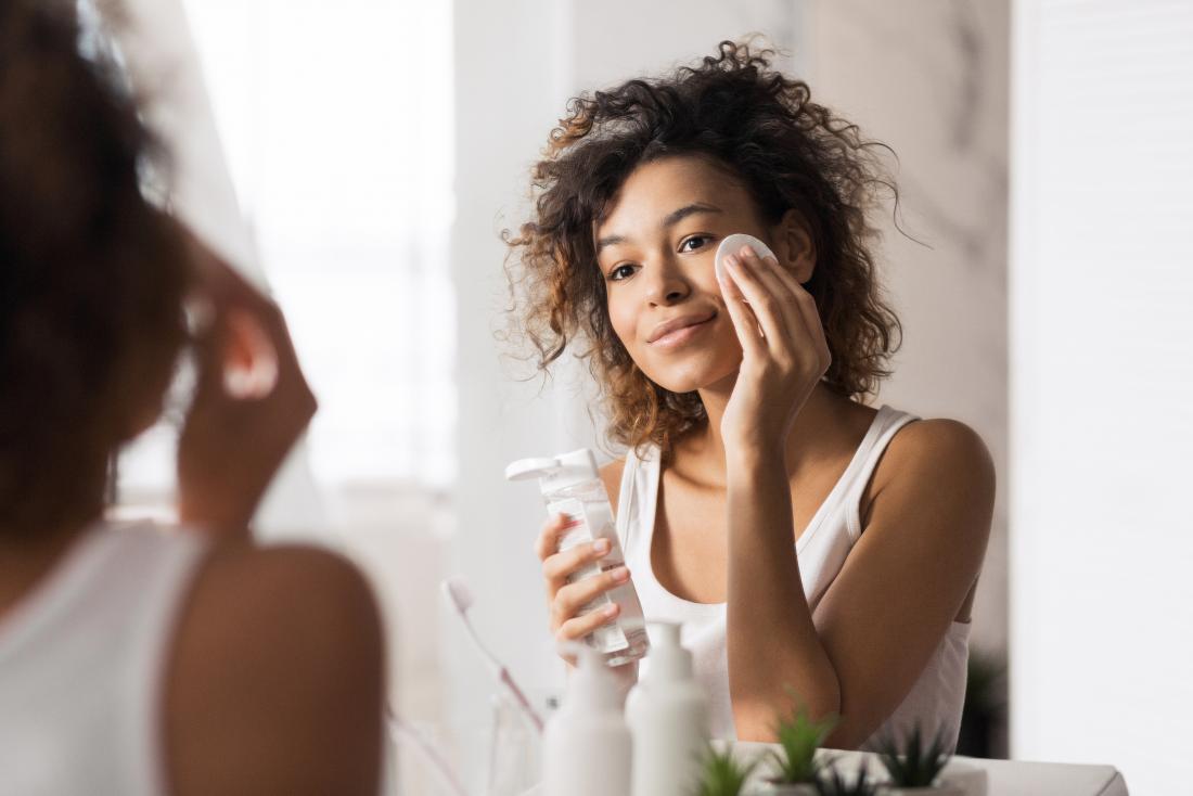 young woman using face cleanser for black skin care