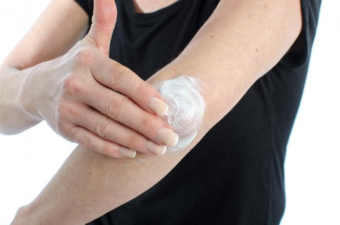 moisturizing cream being applied to an elbow
