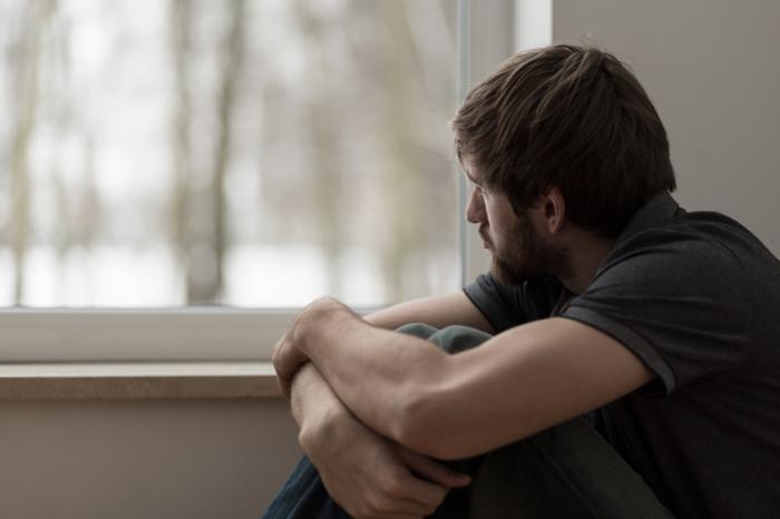 man with depression looking out of window