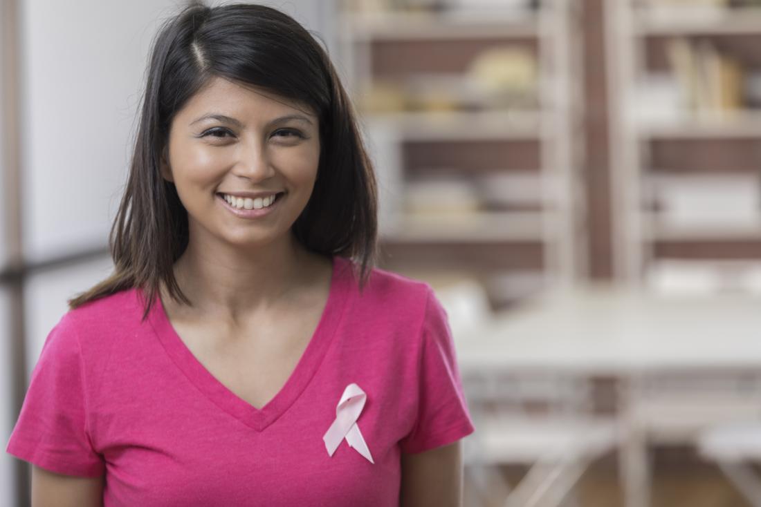 woman wearing breast cancer ribbon smiling at camera
